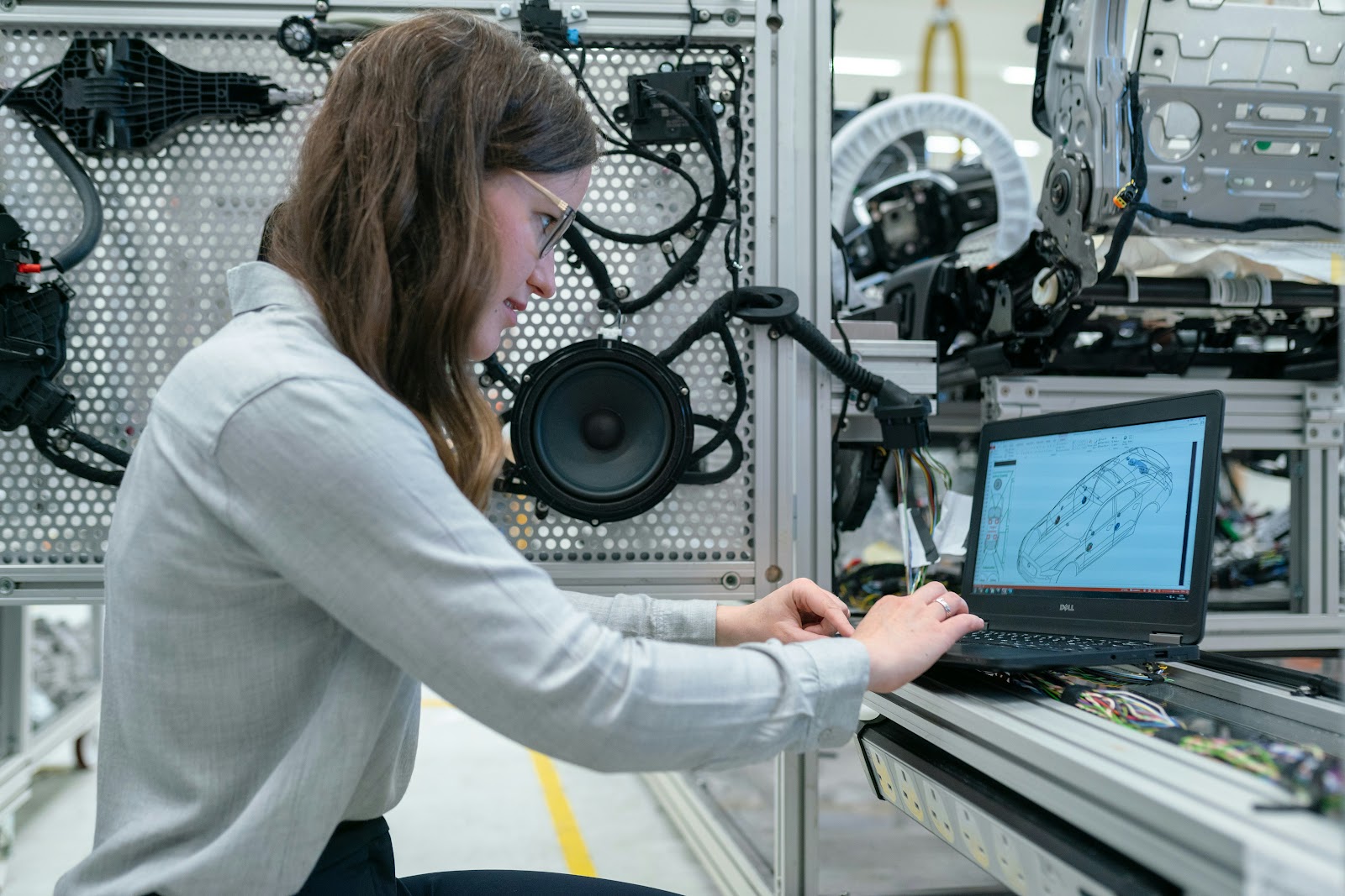 Frau, die am Computer sitzt und ein Auto designed, im Hintergrund technische Geräte