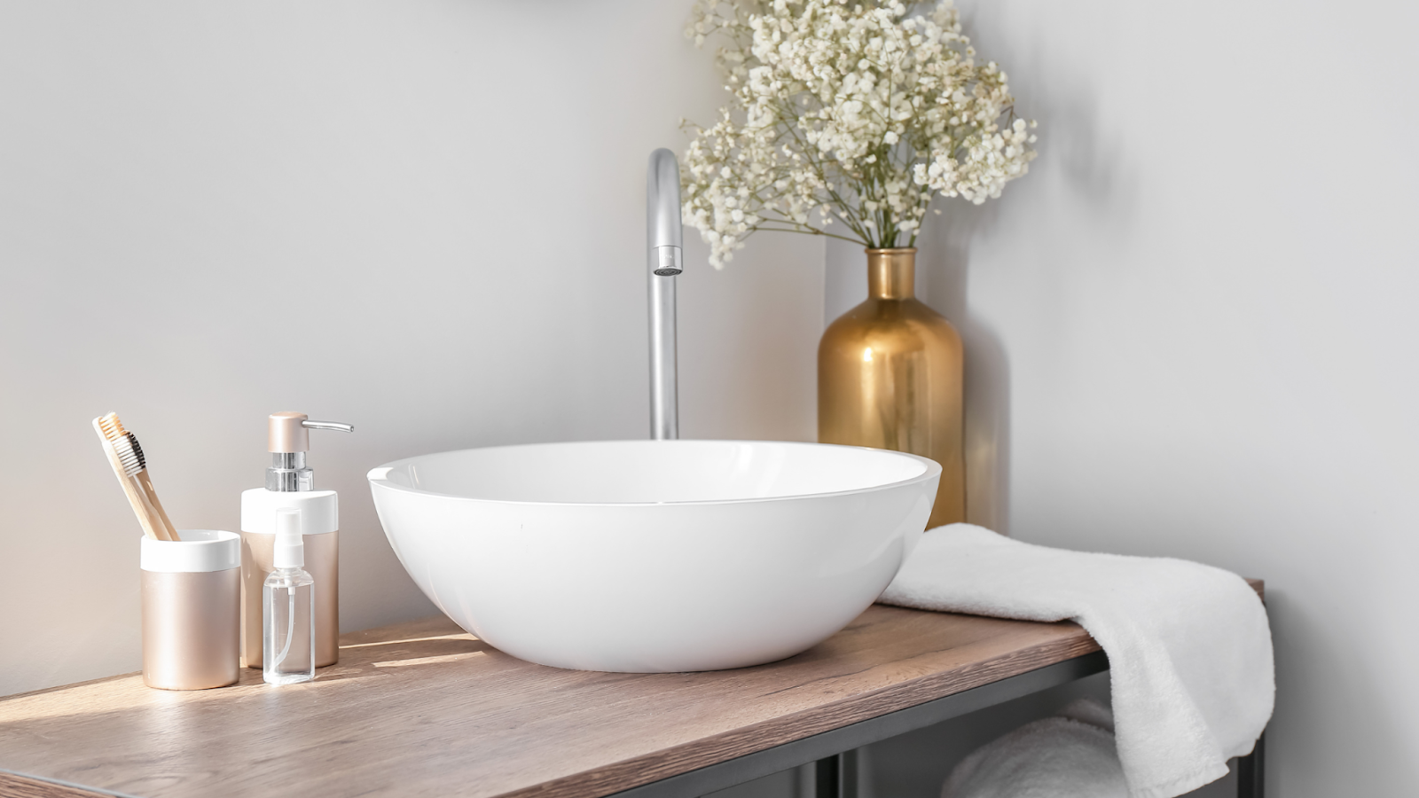 A round white basin on a wooden counter top in a bathroom.